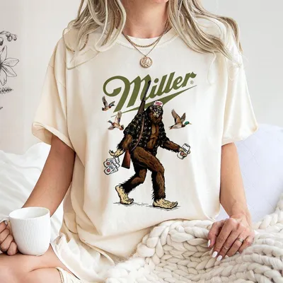 Miller Lite Bigfoot Hunter T-Shirt Bold Bigfoot Graphic With Camo Jacket And Beer Fun And Humorous Desig